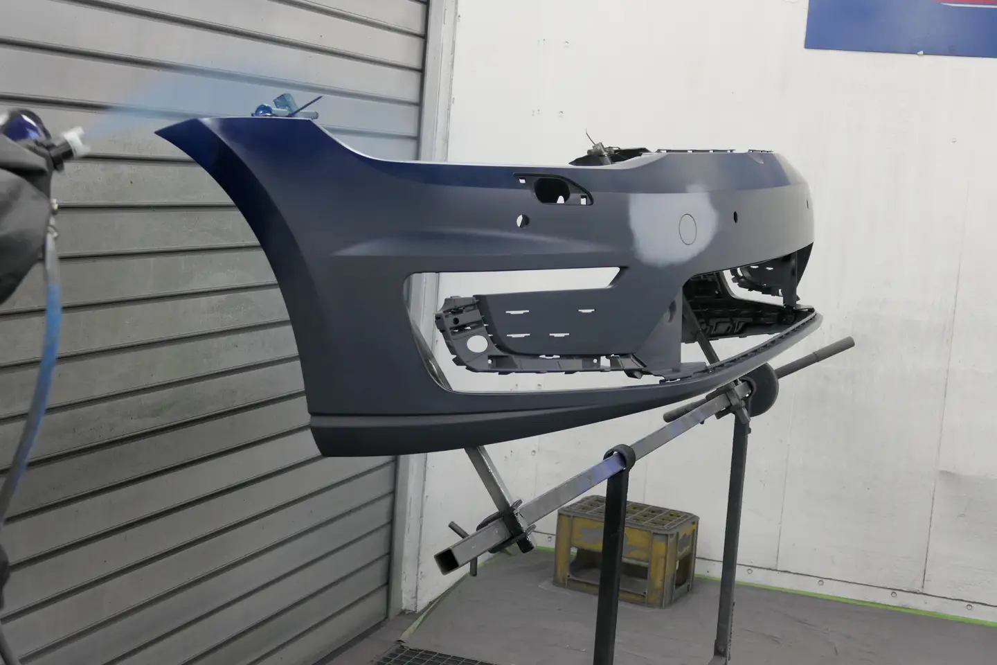 Impressionen demontierte Stoßstange auf einem Ständer,
 zum Lackieren in der Lackierkabine